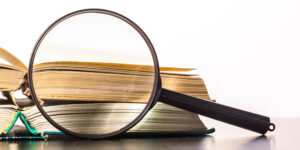 Magnifying glass on a desk in front of two open books.