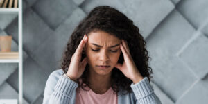 Young women with her hands on her head looking stressed.