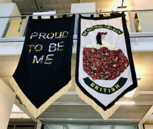 Two large pendants. One says 'Proud to be me' and one says 'Beautiful Black British'.