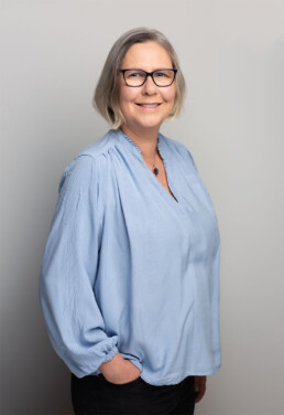 Emma standing with hands in her pockets wearing a blue shirt.