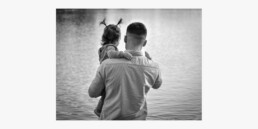 Black and white photo of Harry and his child looking out at a lake.